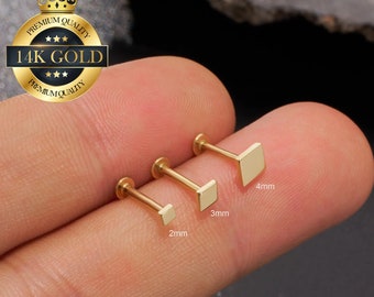 Puede incluir: Tres pendientes de botón cuadrados de oro en diferentes tamaños: 2 mm, 3 mm y 4 mm. Los pendientes se muestran en un dedo.