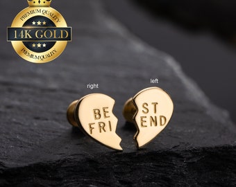 Puede incluir: Dos pendientes de corazón de oro con las palabras "Best Friend" divididas entre ellos. El pendiente izquierdo dice "Best" y el pendiente derecho dice "Friend".