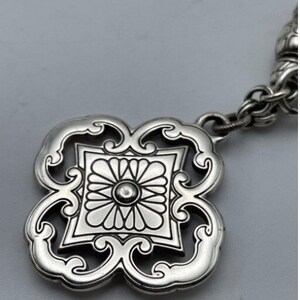 May include: A silver pendant with a detailed floral design. The pendant is attached to a silver chain.
