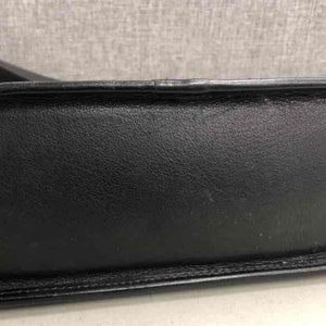 Pu&ograve; includere: Borsa a mano in pelle nera con manico superiore e chiusura a lembo.