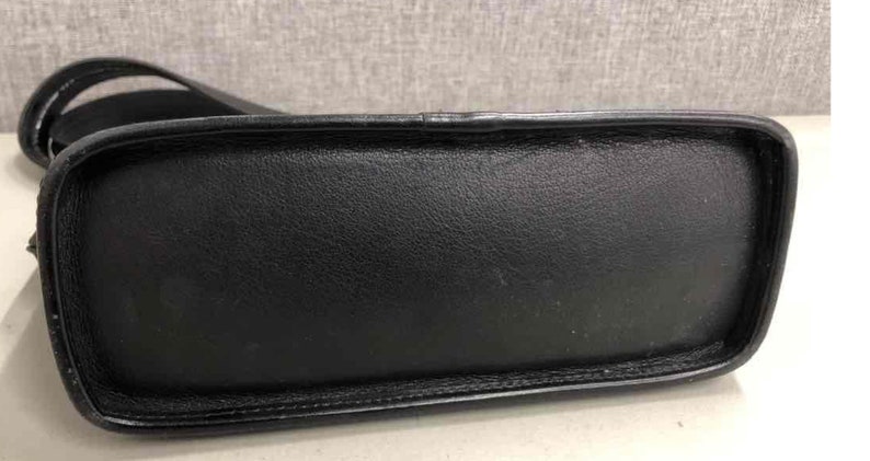 Pu&ograve; includere: Borsa a mano in pelle nera con manico superiore e chiusura a lembo.