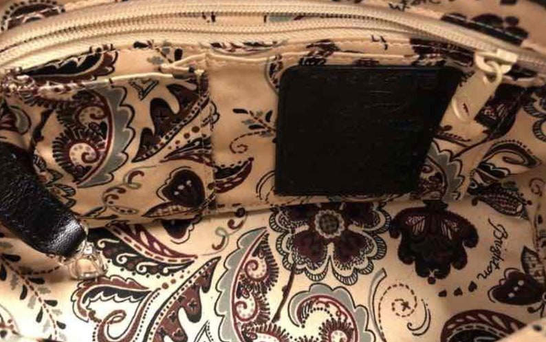 Pu&ograve; includere: L'interno di una borsa a mano con motivo paisley con una cerniera nera e una tasca nera con la scritta "Brighton" stampata.