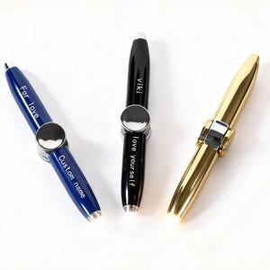 May include: Three pens in blue, black, and gold. The blue pen has the text "For love" and "Custom name". The black pen has the text "viki" and "love yourself". The gold pen is solid gold.