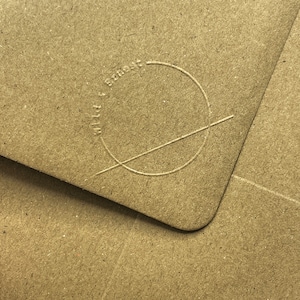 May include: Close-up of a brown paper envelope with a circle and a line drawn through it. The circle has the text "Made with love & smarts" written around it.