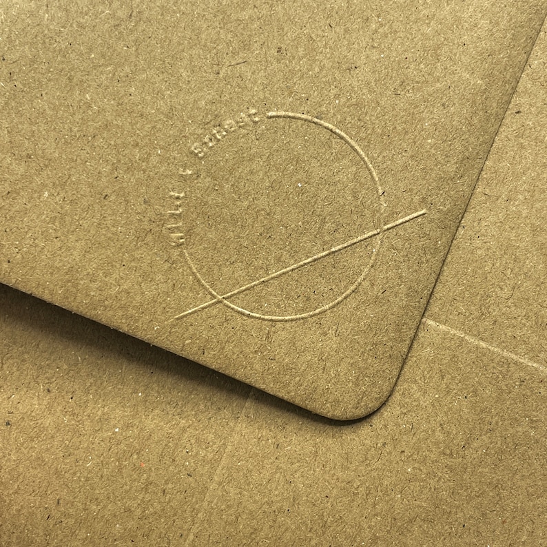 May include: Close-up of a brown paper envelope with a circle and a line drawn through it. The circle has the text "Made with love & smarts" written around it.