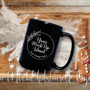 May include: Black coffee mug with a white design that says "Your Mock Up Island" and "Your Design Here". The mug is sitting on a wooden surface with flour scattered around it.