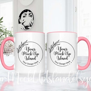 May include: Two white ceramic mugs with pink rims and handles. Each mug has a black circle with the text "Your Mock Up Island" and "Your Design Here" in black text.
