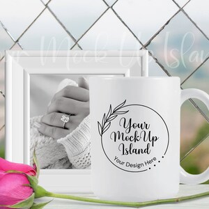 May include: White ceramic mug with a black circle design that says "Your Mock Up Island" and "Your Design Here". The mug is sitting on a white surface with a pink rose and a white picture frame.