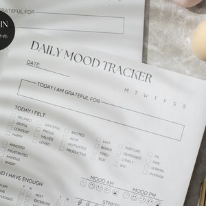 May include: A black and white printable daily mood tracker with sections for gratitude, feelings, and mood. The tracker includes a calendar for tracking daily moods.
