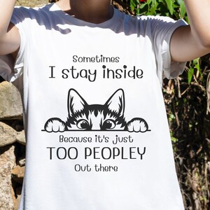 May include: White t-shirt with a black and white cat peeking over the top. The text on the shirt reads "Sometimes I stay inside because it's just too peopley out there."