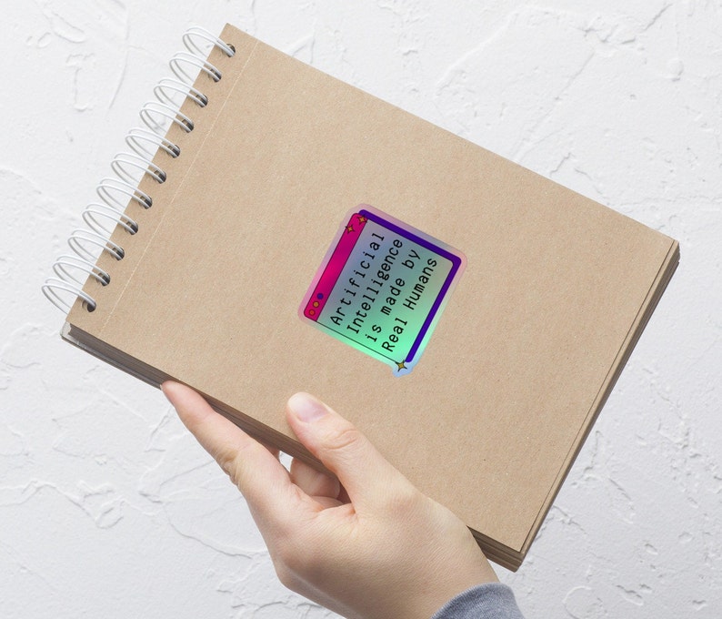 May include: A brown notebook with a spiral binding and a holographic sticker that says "Artificial Intelligence is made by Real Humans".