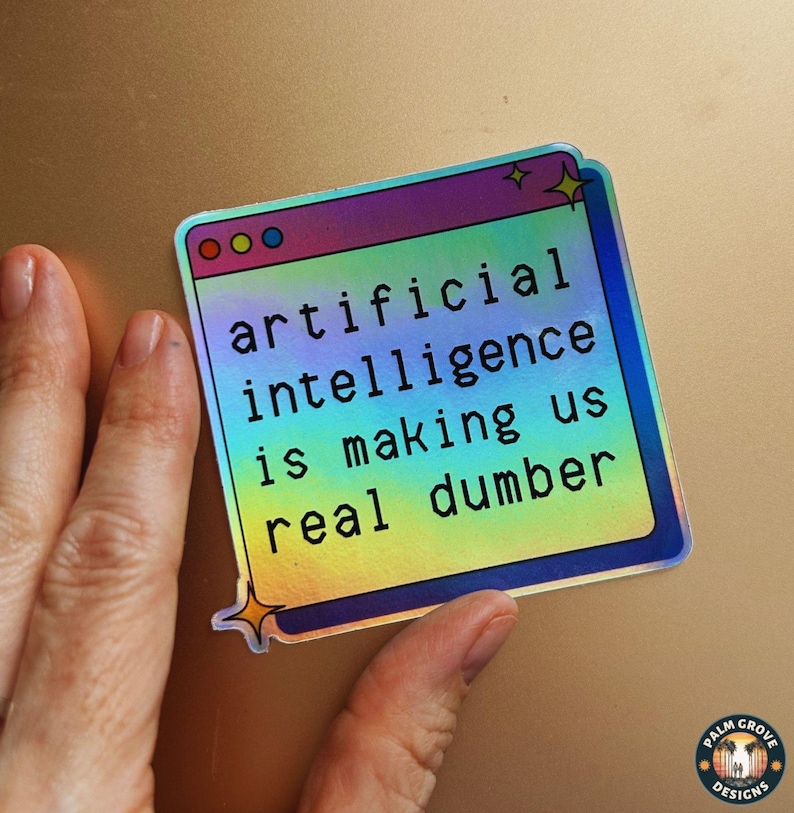 May include: A holographic sticker with the text "artificial intelligence is making us real dumber." The sticker is in the shape of a computer window with a colorful gradient background and star accents.