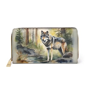 Puede incluir: Cartera beige con una pintura de acuarela de un lobo de pie cerca de un arroyo en un bosque. El lobo tiene pelaje gris, negro y marrón. La cartera tiene una cremallera y un tirador dorados.