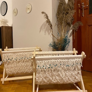 Puede incluir: Dos tapices de macramé blancos con cuentas verdes en marcos de madera. Los tapices tienen un patrón de diamante y se muestran en un suelo de madera.