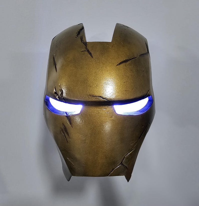 May include: A gold-coloured Iron Man mask with a distressed finish and glowing blue eyes.