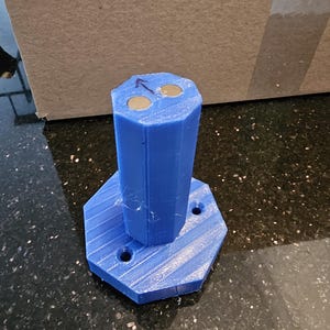 May include: A blue 3D printed octagonal base with three holes and a blue 3D printed cylinder with two round magnets on top.