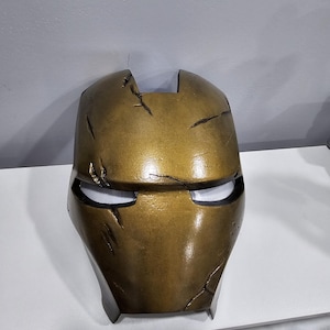 May include: A gold-coloured, weathered, plastic Iron Man mask with a black visor.