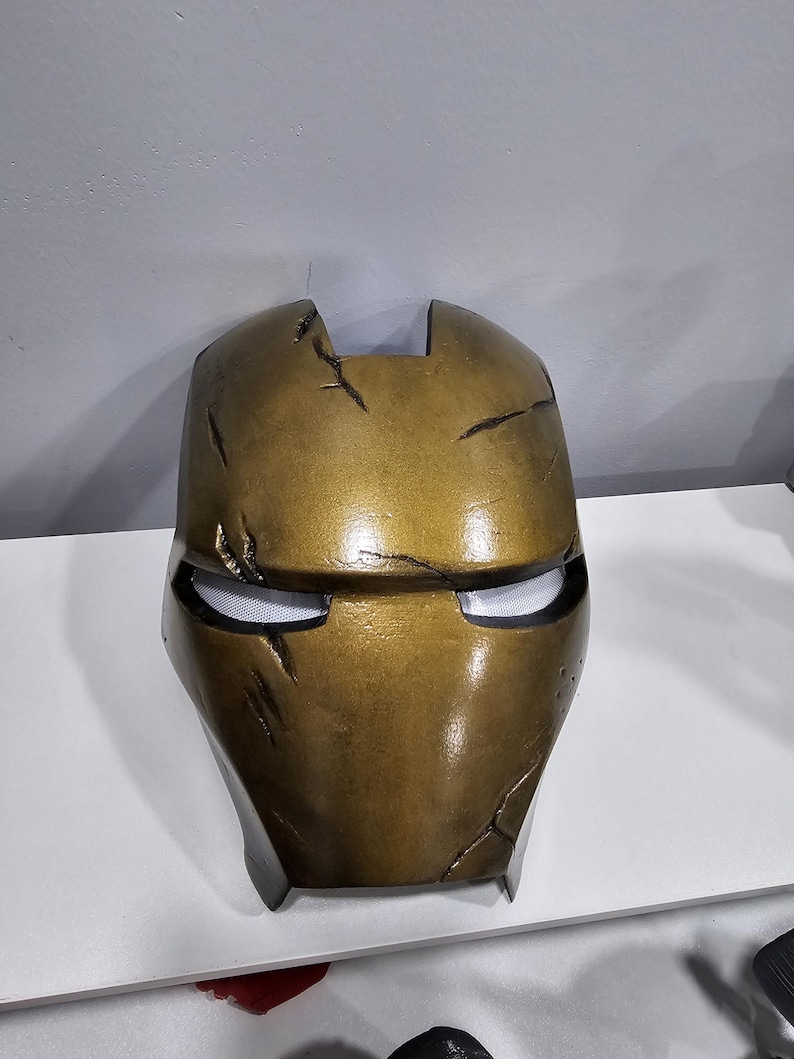 May include: A gold-coloured, weathered, plastic Iron Man mask with a black visor.