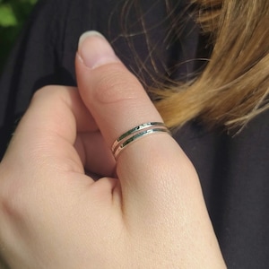 Könnte beinhalten: Ein silberner Daumenring mit gehämmerter Oberfläche. Der Ring wird am Daumen einer Hand getragen.