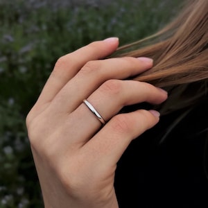 Könnte beinhalten: Ein schlichter Silberring, der an einem Finger getragen wird.