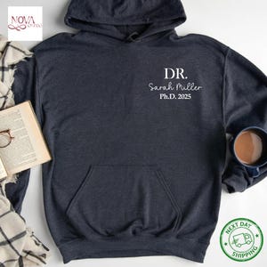 May include: A dark blue hooded sweatshirt with the text "DR. Sarah Miller Ph.D. 2025" printed on the front.