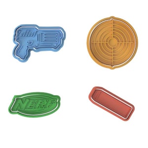 Puede incluir: Un juego de cuatro cortadores de galletas de plástico azul, naranja, verde y rojo con forma de pistola Nerf, diana, logotipo de Nerf y dardo Nerf.