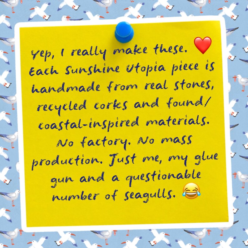 May include: A bright yellow square note pinned with a blue thumbtack, featuring dark blue handwritten text: Yep, I really make these. Each Sunshine Utopia piece is handmade from real stones, recycled corks and found/coastal-inspired materials.