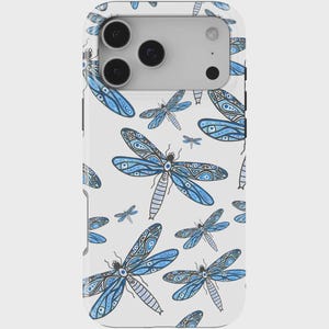 Puede incluir: Funda de teléfono blanca con un patrón repetido de libélulas azules. Las libélulas tienen patrones de alas detallados y son de varios tamaños. La funda del teléfono tiene un módulo de cámara con tres lentes.