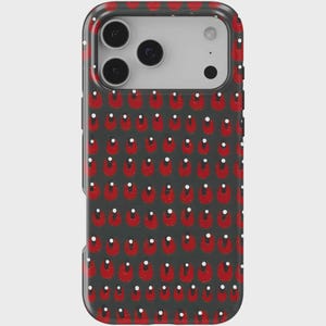 May include: A smartphone case featuring a repeating pattern of red shapes with white dots on a dark grey background. The case has a black border and cutouts for the phone's camera lenses.