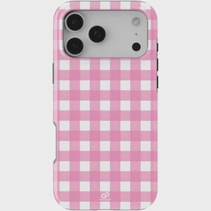Puede incluir: Funda de teléfono con estampado de cuadros rosa y blanco. La funda tiene un acabado brillante y un recorte de cámara para una cámara de triple lente. La funda tiene un pequeño logotipo en la parte inferior.