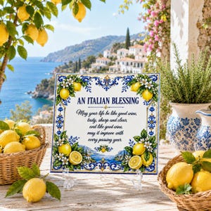 Könnte beinhalten: Eine quadratische Dekofliese mit blau-goldener Blumenbordüre und dem Text: AN ITALIAN BLESSING. May your life be like good wine, tasty, sharp and clear, and like good wine, may it improve with every passing year. Die Fliese steht auf einem Ständer.