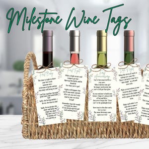 Puede incluir: Una cesta de mimbre contiene cinco botellas de vino, cada una con un vino de diferente color y una etiqueta decorativa. Las etiquetas tienen diseños florales y texto, incluyendo "First Baby", "First Fight" y "First Anniversary".