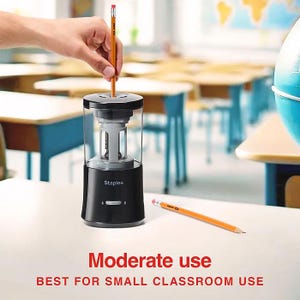 May include: A black Staples electric pencil sharpener with a clear plastic chamber. A hand inserts a yellow pencil into the sharpener. The text "Moderate use" and "BEST FOR SMALL CLASSROOM USE" is displayed below the sharpener.
