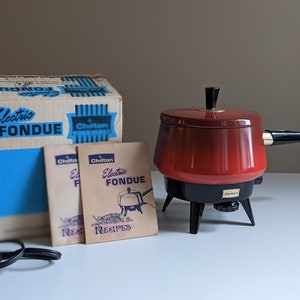 May include: Vintage Chilton Electric Fondue set with a red pot, black base, and a cord. The set comes with two recipe booklets.