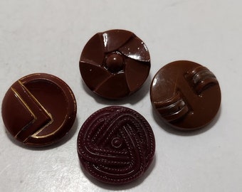 May include: Four brown and maroon plastic buttons with different designs. The buttons are round and have a raised design.