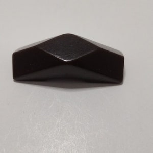 May include: A dark brown, geometrically shaped cabinet knob.