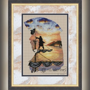 Puede incluir: Un patrón de punto de cruz que presenta una silueta de una persona izando una bandera en un barco al atardecer. El patrón está enmarcado en un marco de madera oscura con un borde interior dorado. El patrón es de mandarims design.