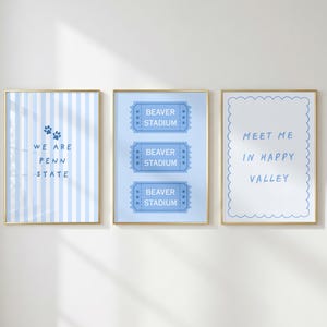 May include: Three vertical wall art prints in gold frames. The left print has blue stripes and text reading WE ARE PENN STATE with paw prints. The center print shows three blue ticket stubs labeled BEAVER STADIUM. The right print says MEET ME IN HAPPY VALLEY.