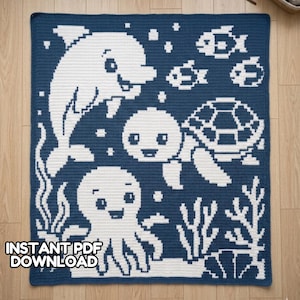 May include: A square, navy blue and white crochet blanket featuring an underwater scene. The design includes a dolphin, fish, a turtle, an octopus, and seaweed. The text "INSTANT PDF DOWNLOAD" is at the bottom left.