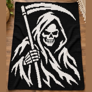 Può includere: Una coperta rettangolare all'uncinetto con un design ad alto contrasto in bianco e nero. Il grafico raffigura una figura con teschio e cappuccio, il tristo mietitore, che tiene in mano una lunga falce. Il motivo è creato con punti visibili.