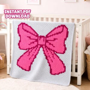 May include: A light grey baby blanket featuring a large pink bow design. The bow has a darker pink outline and a pixelated appearance. The blanket is draped over a white cot. Text in the upper left corner reads "INSTANT PDF DOWNLOAD".