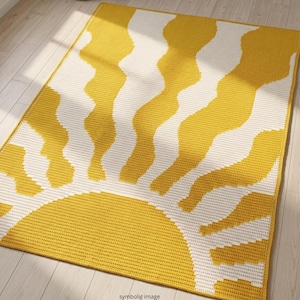 May include: A rectangular rug with a sun design. The rug features a yellow sun with white wavy lines against a white background. The rug is made of a woven material and is placed on a wooden floor. The words "symbolic image" are at the bottom.