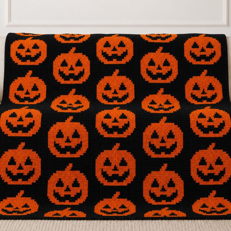 May include: A black crochet blanket featuring a repeating pattern of orange jack-o'-lanterns. The design consists of multiple rows of pumpkins with triangular eyes, noses, and jagged mouths arranged in a grid across the entire textile surface.