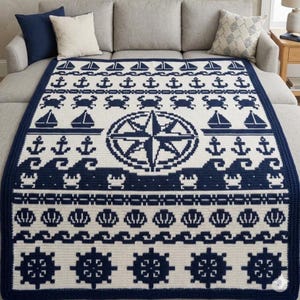 Könnte beinhalten: Eine rechteckige Häkeldecke mit nautischem Motiv in einer Farbpalette aus Marineblau und Creme. Das Design zeigt sich wiederholende Reihen von Segelbooten, Ankern, Krabben, Wellen, Muscheln und Steuerrädern mit einer Kompassrose.