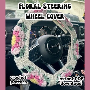 May include: A crocheted floral steering wheel cover in a vehicle. The cover is white with pink, yellow, and green floral accents. Text on the image reads "FLORAL STEERING WHEEL COVER", "crochet pattern", and "instant PDF download".