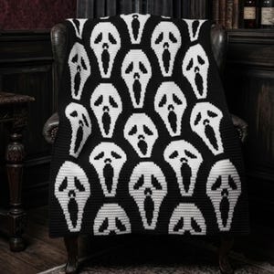 Può includere: Coperta lavorata a maglia in bianco e nero con un motivo ripetuto di maschere di Ghostface. La coperta è drappeggiata su una poltrona in pelle scura, creando un pezzo decorativo spettrale. Perfetta per Halloween o gli appassionati di horror.