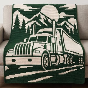 May include: A dark green and cream crochet blanket featuring a large semi-truck in the foreground. The background displays a landscape with a circular sun, jagged mountain peaks, and evergreen trees, all rendered in a two-tone pixelated style.
