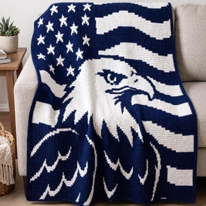 May include: A rectangular crochet blanket featuring a dark navy blue and white color scheme. The design displays a large, detailed white bald eagle head centered over a field of white stars and horizontal stripes on a dark navy blue background.