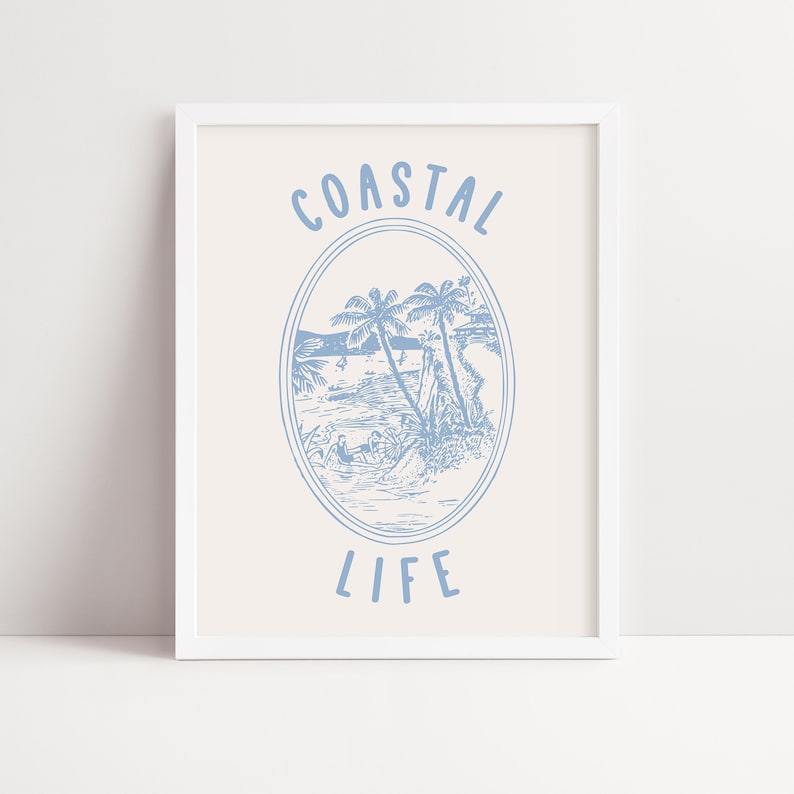 May include: A white framed print with a blue illustration of palm trees and a beach scene. The text "COASTAL LIFE" is written in blue below the illustration.