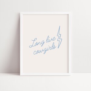 May include: A white framed print with a light blue lightning bolt and the text "Long live cowgirls" in a cursive font.